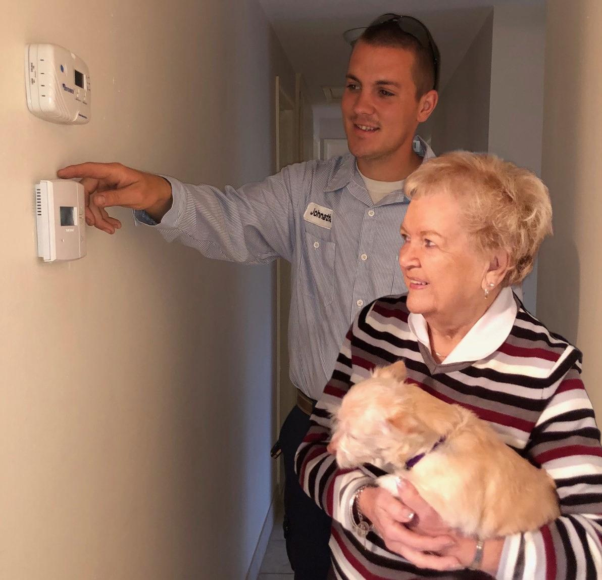 Technician showing customer how to use thermostat