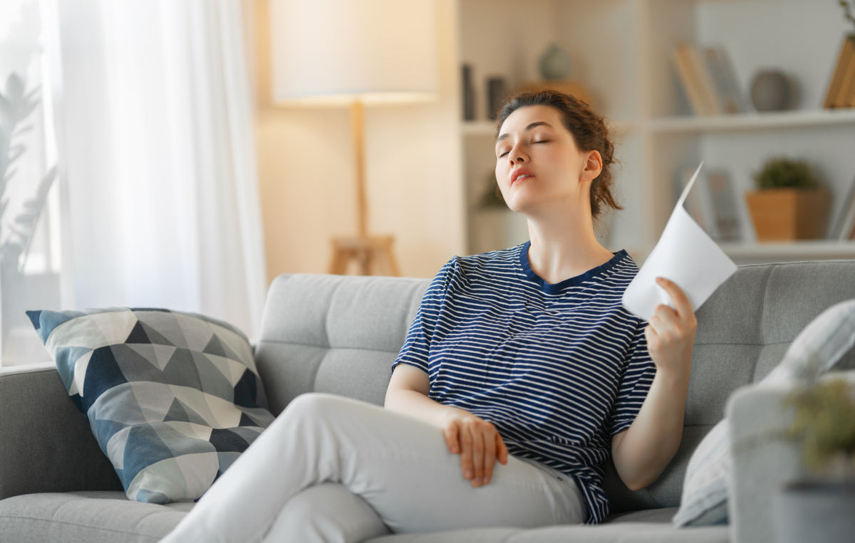 Woman fanning herself while sitting on a couch