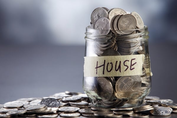 Coins overflowing a jar with house written on tape on the jar